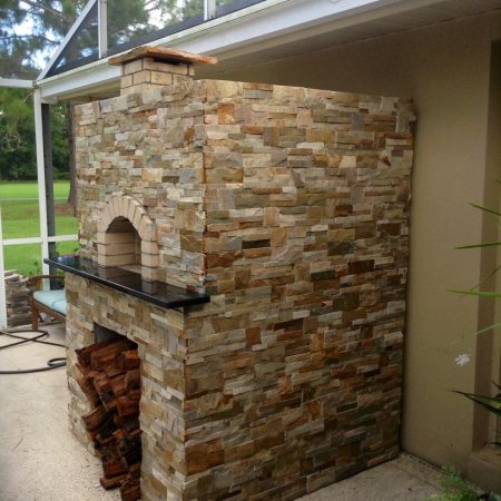Brick dome pizza oven complete with stone a stone finish and wood storage.