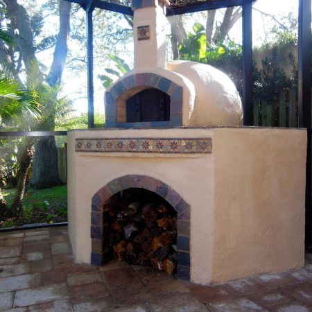 Outdoor wood-fired pizza oven with brown tile accents.