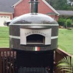 An outdoor pizza oven finished with black and white glass tiles and a custom engraved plate