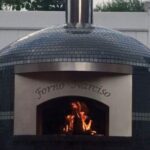 An outdoor pizza oven with a glass tile finish and a custom engraving