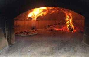 Pizza cooking inside a traditional pizza oven by rolling fire with gas assistance
