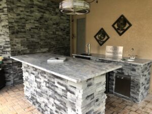 Forno Nardona Tampa built outdoor kitchen/bar made of stone, granite and Lion stainless accessories with island and personalized plate "Casa Summerelli" sign.