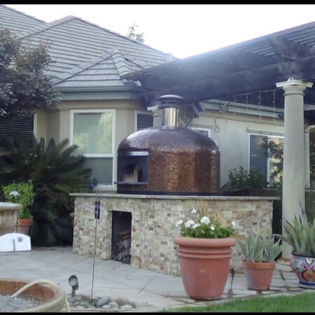Forno Nardona Napoli pizza oven with copper glass tile sitting on top of a customer built base with stone and granite surfaces.
