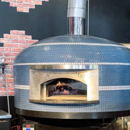 Blue glass tiled Commercial Nardona Napoli oven with white stripes and personalized face plate that says, "Let's Go Bolts!" It sits on a custom black stand and has an automatic gas burner.