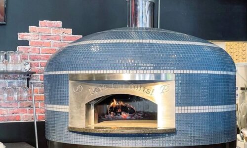 Blue glass tiled Commercial Nardona Napoli oven with white stripes and personalized face plate that says, "Let's Go Bolts!" It sits on a custom black stand and has an automatic gas burner.