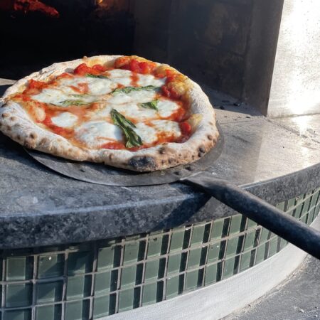 Naples style pizza on a turning peel at the exit of the pizza oven