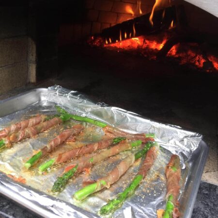 Prosciutto wrapped asparagus on a cooking sheet fresh from the Nardona Napoli oven.