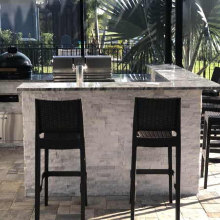 Outdoor bar with a green egg and a grill poolside.