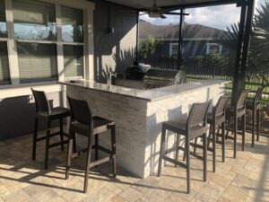 One of our outdoor kitchens with a bar top, a green egg and a grill poolside.