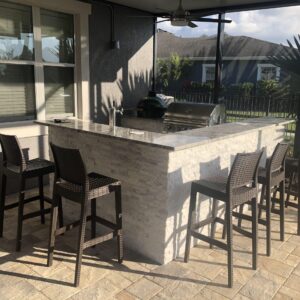 One of our outdoor kitchens with a bar top, a green egg and a grill poolside.