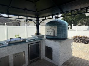 Personalized exterior door on blue 24" Napoli oven by Forno Nardona set in an outdoor kitchen with Lion Premium Accessories.