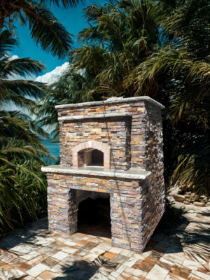 Firenze pizza oven by Forno Nardona on a custom base to store firewood set on a stone patio in a lush tropical setting.